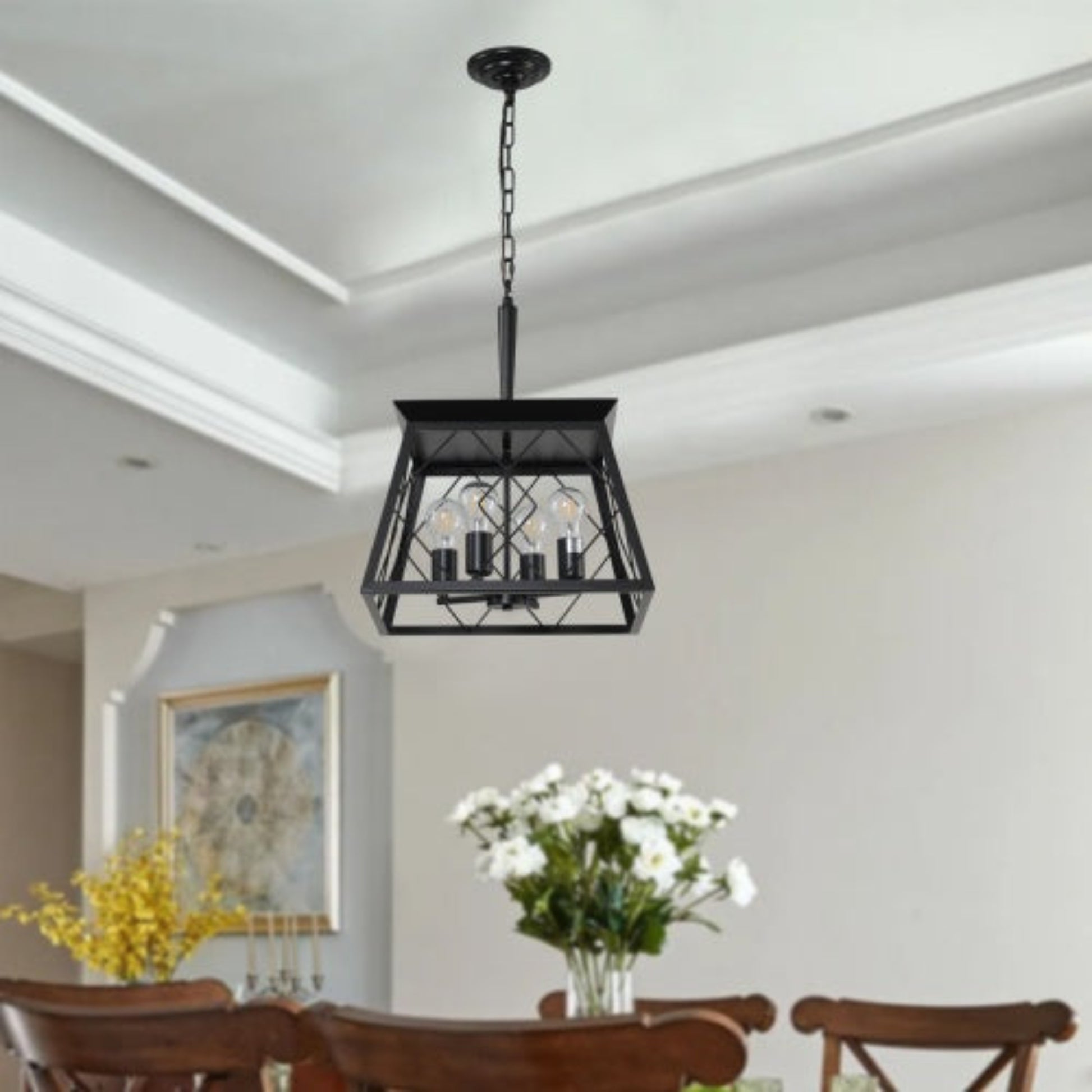Black pendant light fixture hanging in a dining room with wooden chairs and floral arrangements.