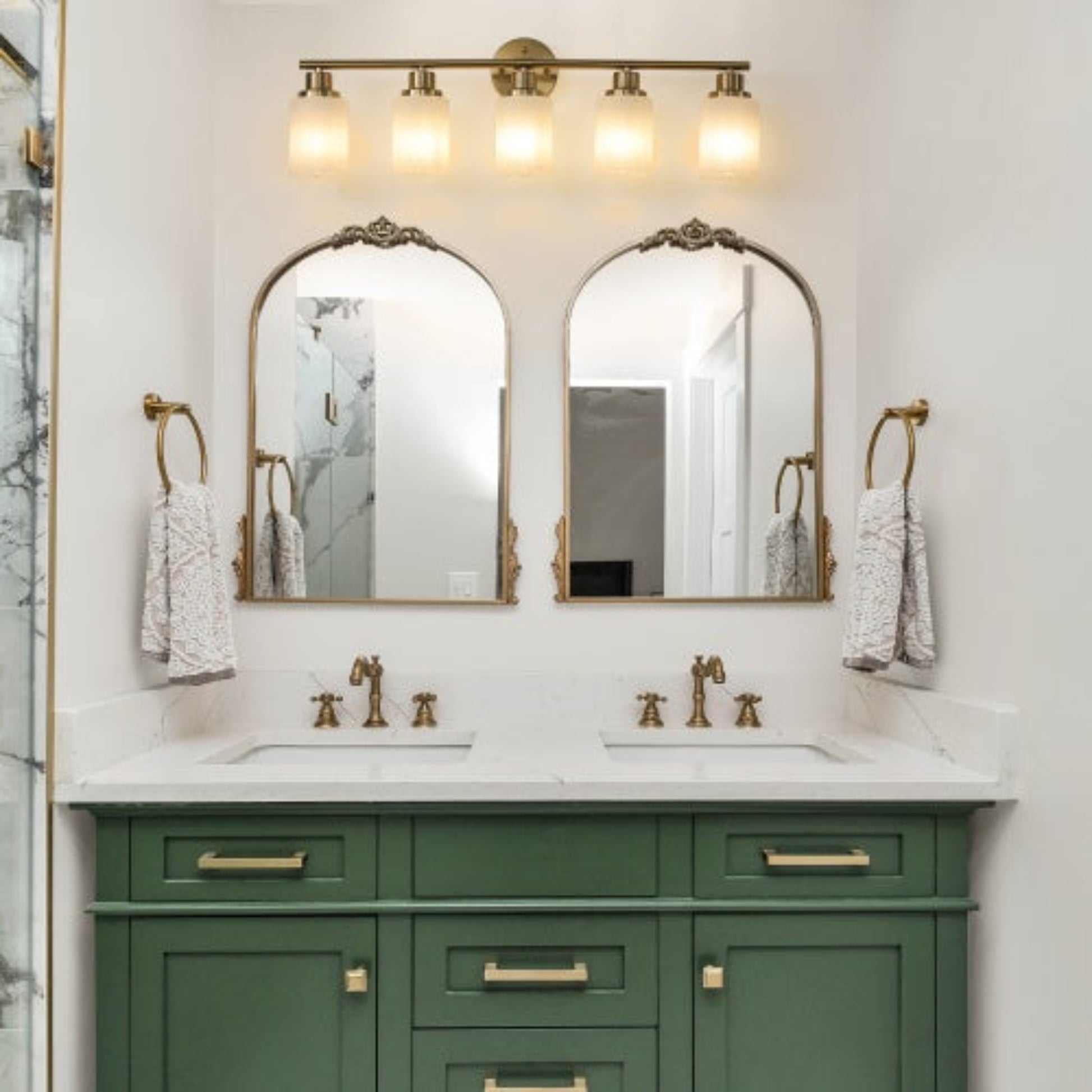 Bathroom vanity with green cabinets, white countertop, and gold fixtures.