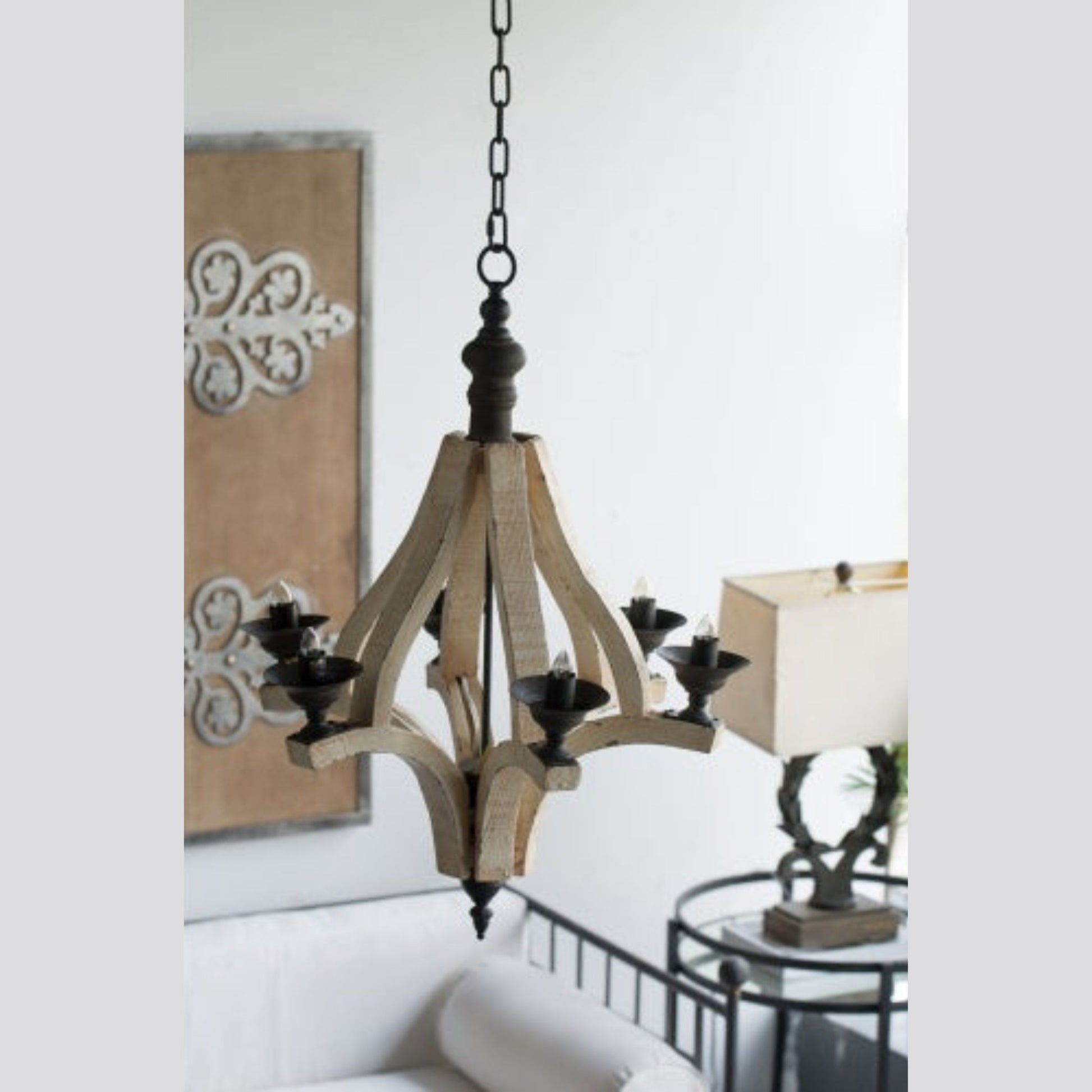 Wooden chandelier hanging in a room with a lamp and wall art.