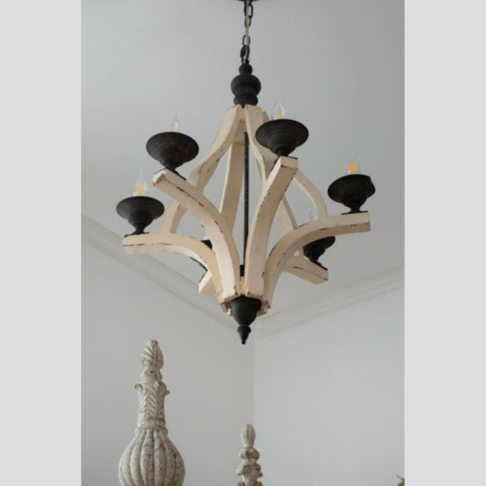 Wooden chandelier with black accents hanging in a room with decorative vases.