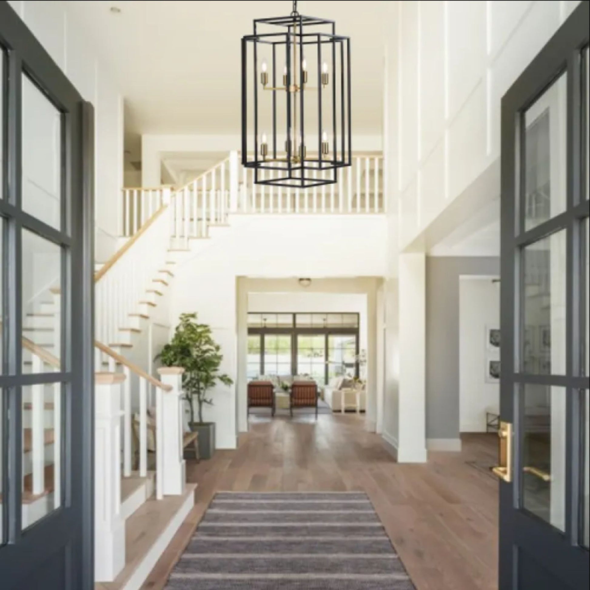 Modern interior of a house with a staircase, chandelier, and open floor plan.