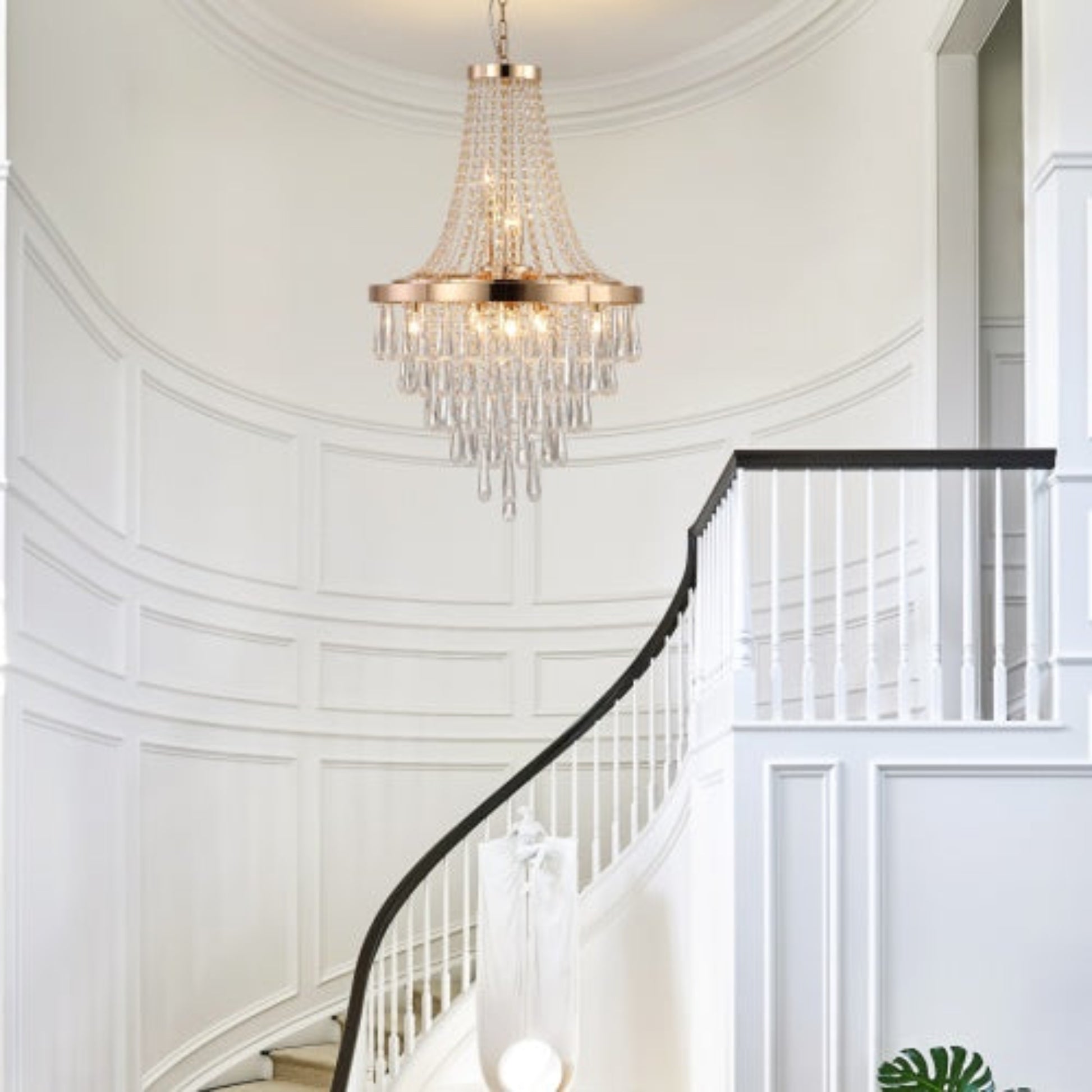 Chandelier hanging above a staircase in a well-lit room with white walls.