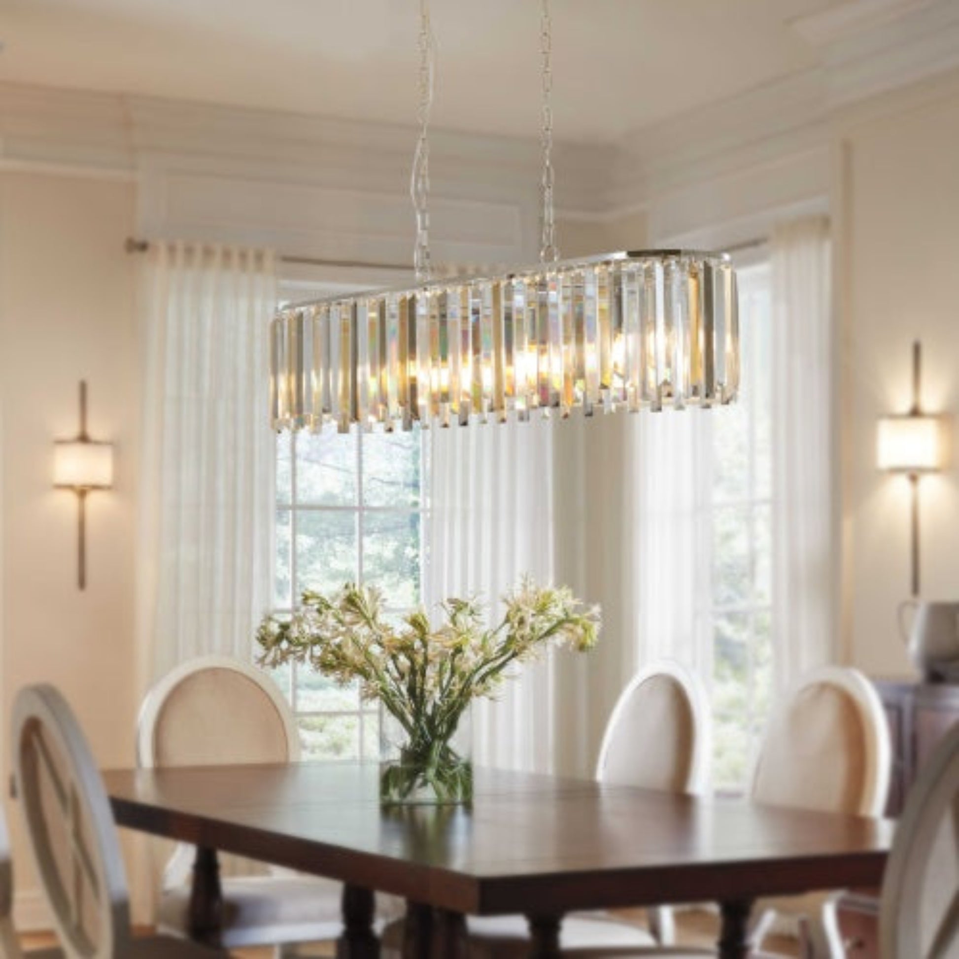 Dining room with a chandelier, table, chairs, and a vase of flowers.