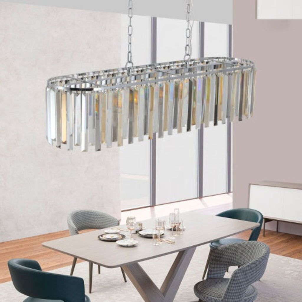 Modern chandelier hanging above a dining table with chairs in a well-lit room.