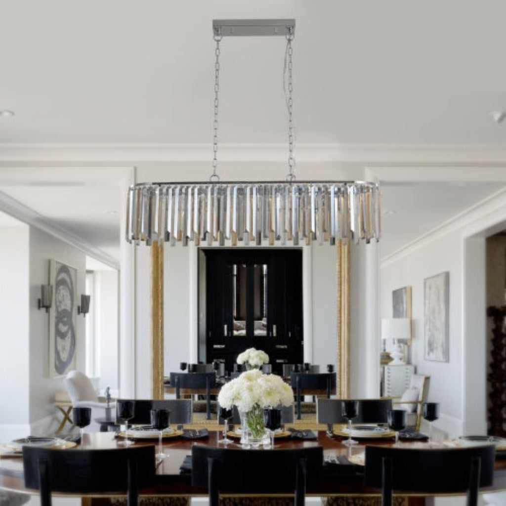 Modern chandelier hanging in a stylish dining room with a table and chairs.