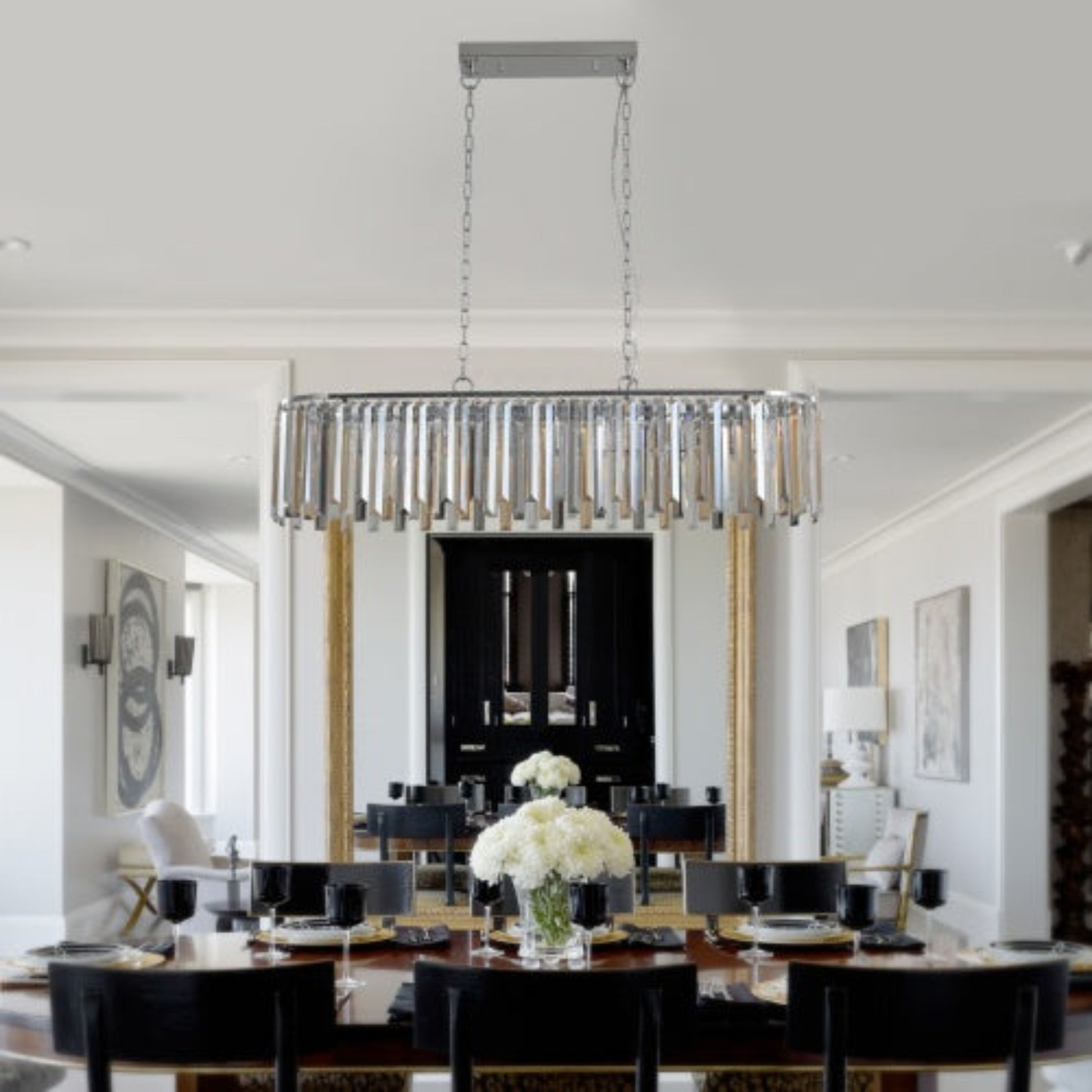 Modern chandelier hanging in a stylish dining room with a table and chairs.