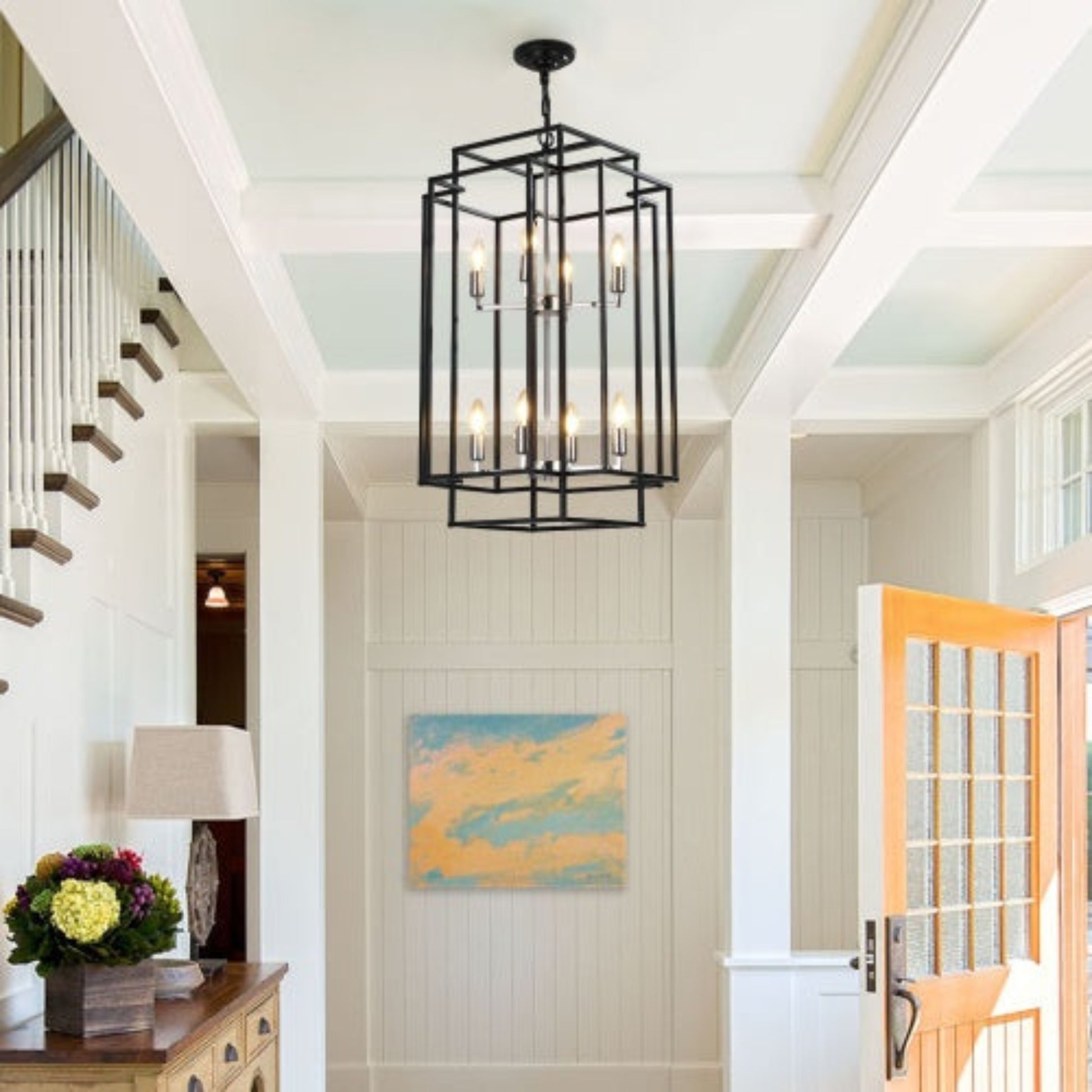 Foyer with a black chandelier, wooden side table, and floral arrangement.