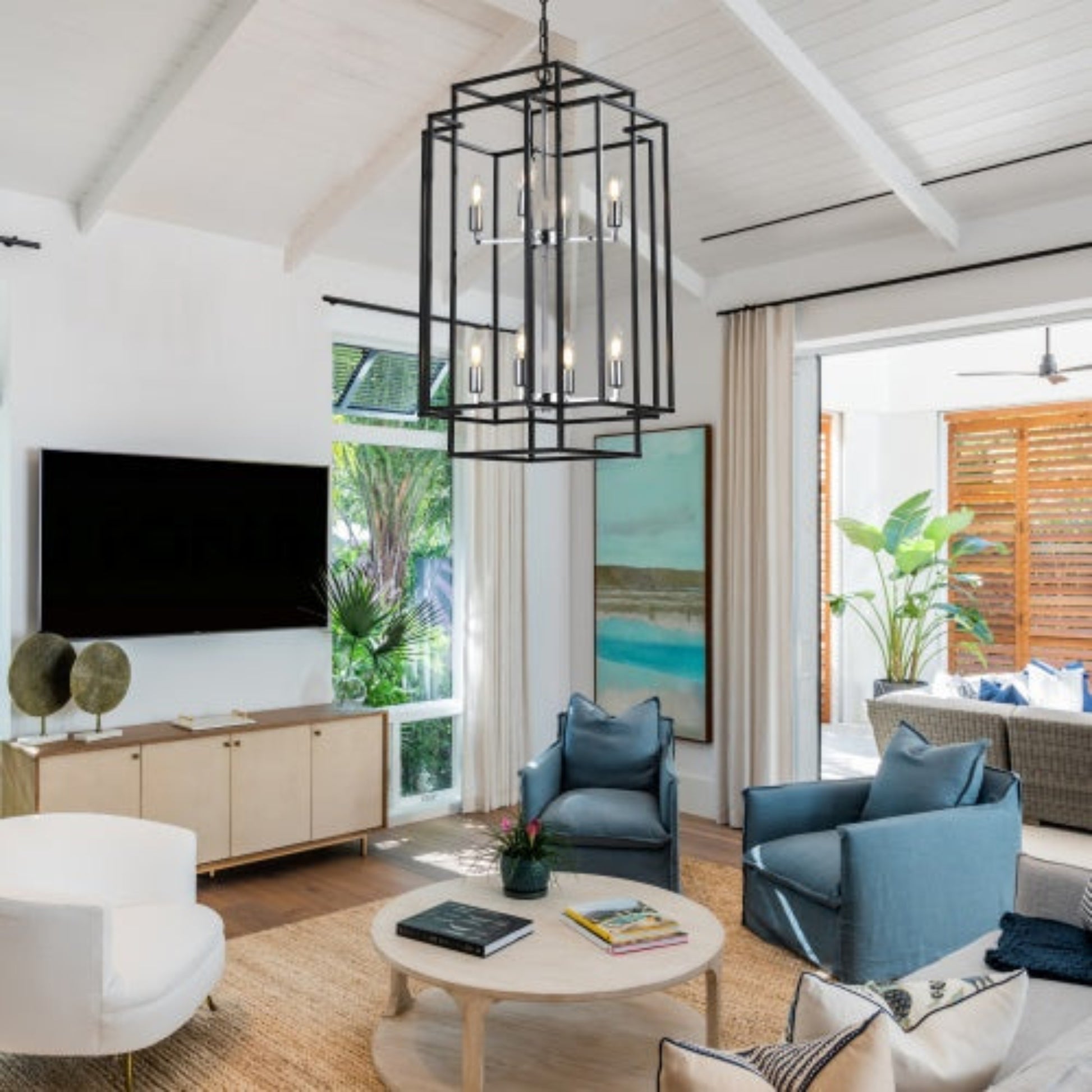 Modern living room with blue chairs, white armchair, and a chandelier.
