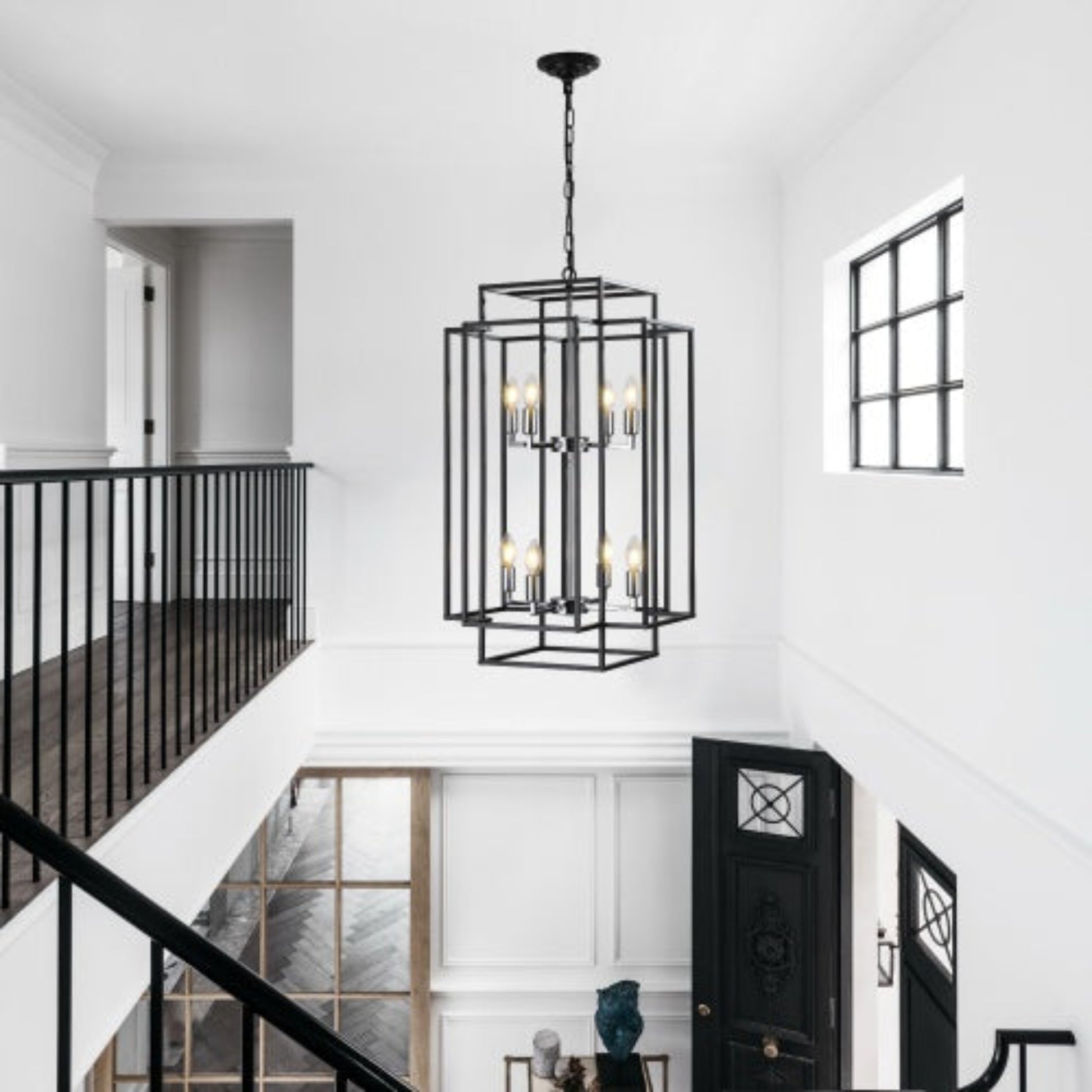 Modern chandelier hanging in a stylish interior with staircase and window.