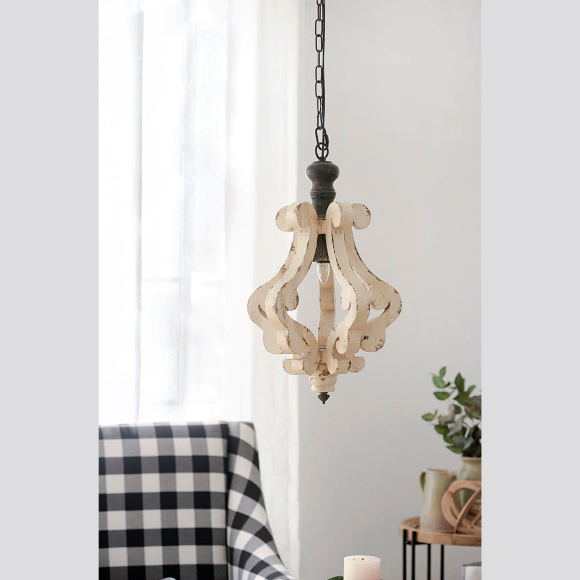 Wooden pendant light hanging in a room with a checkered chair and plant.